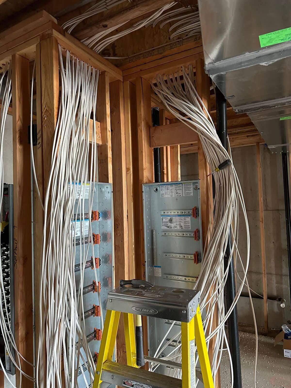 A ladder is sitting in a room with a bunch of wires hanging from the ceiling.