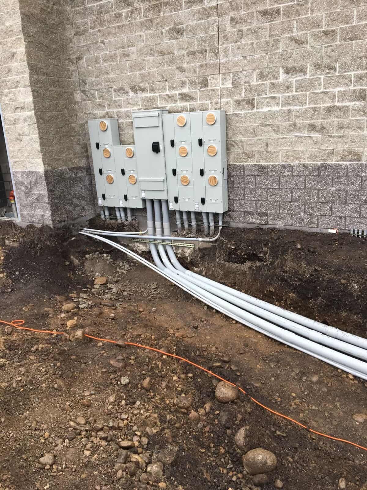 A bunch of electrical boxes are sitting on the side of a brick building.