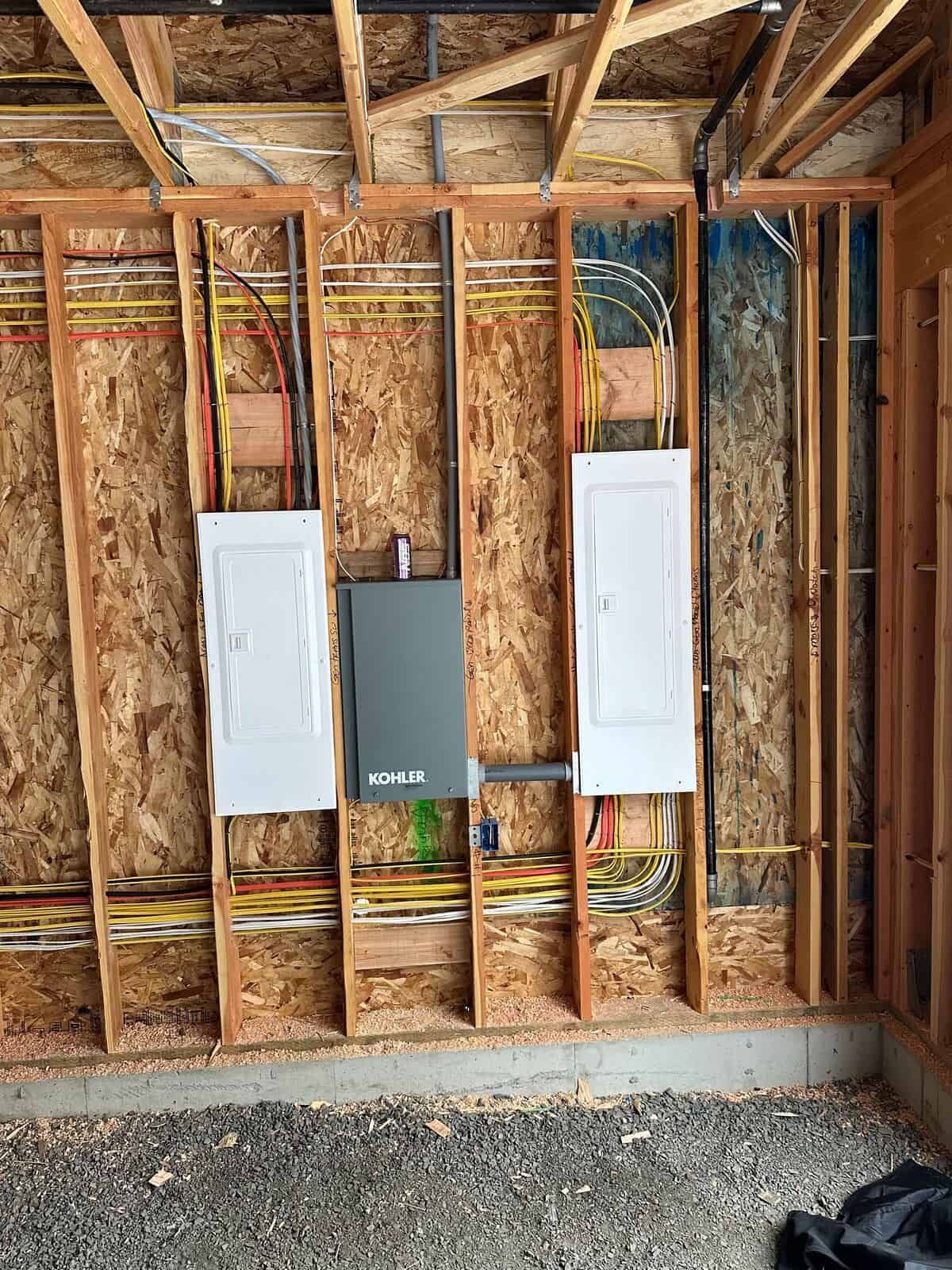 A wooden wall with electrical panels and wires hanging from it.