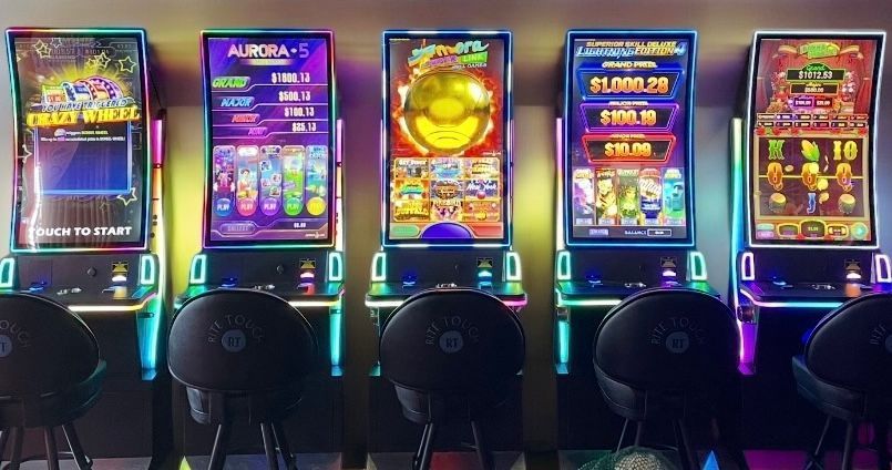 Row of brightly lit arcade game machines with colorful neon screens in a dark room