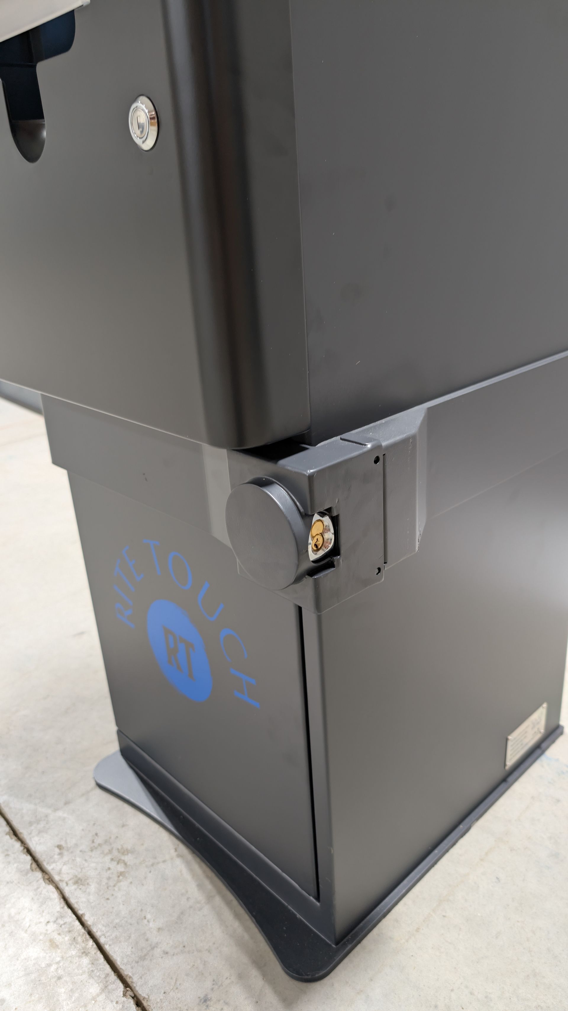 Close-up of a black trash bin with a damaged corner panel and blue recycle symbol.
