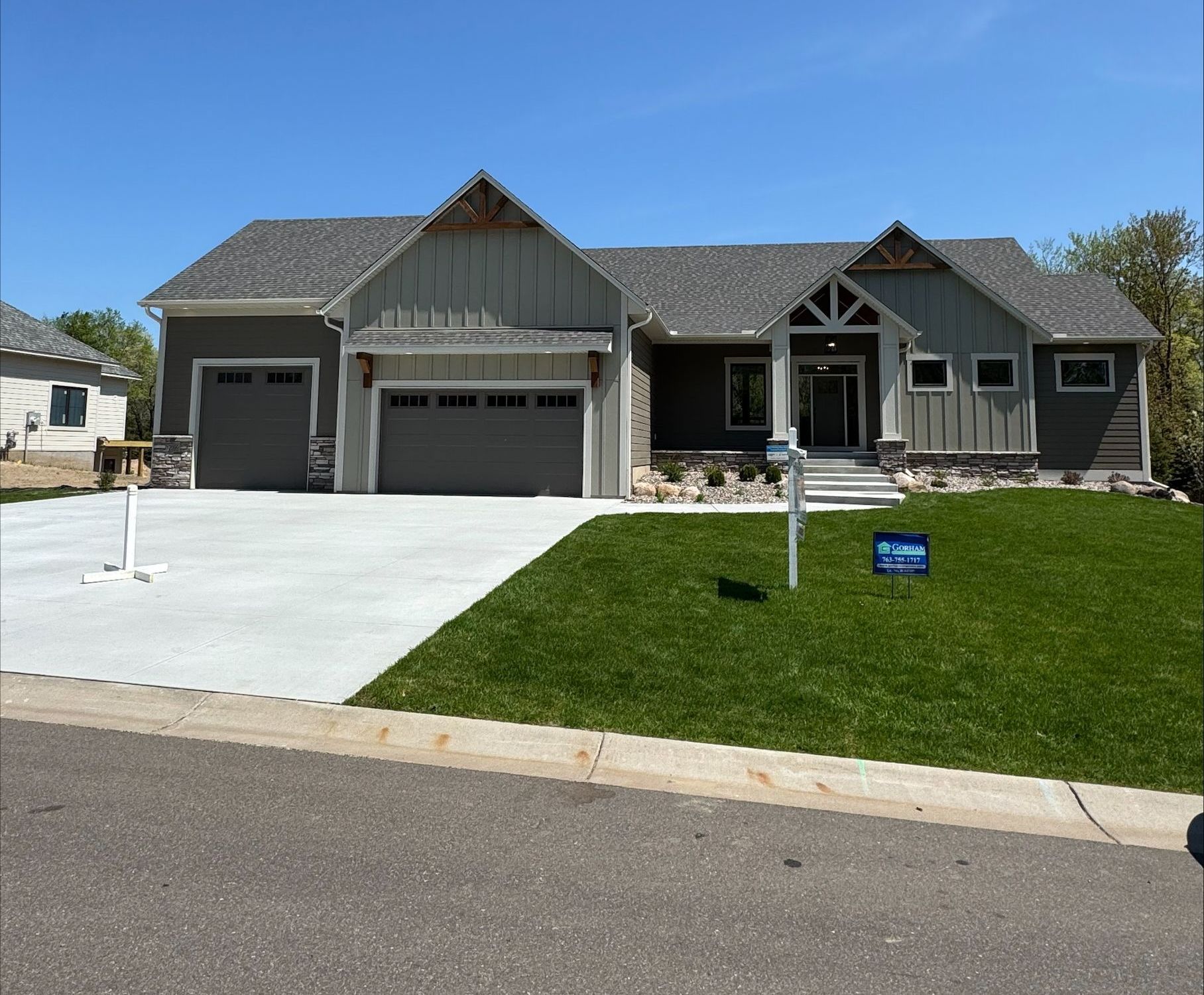 A large house with a concrete driveway and a large lawn in front of it.