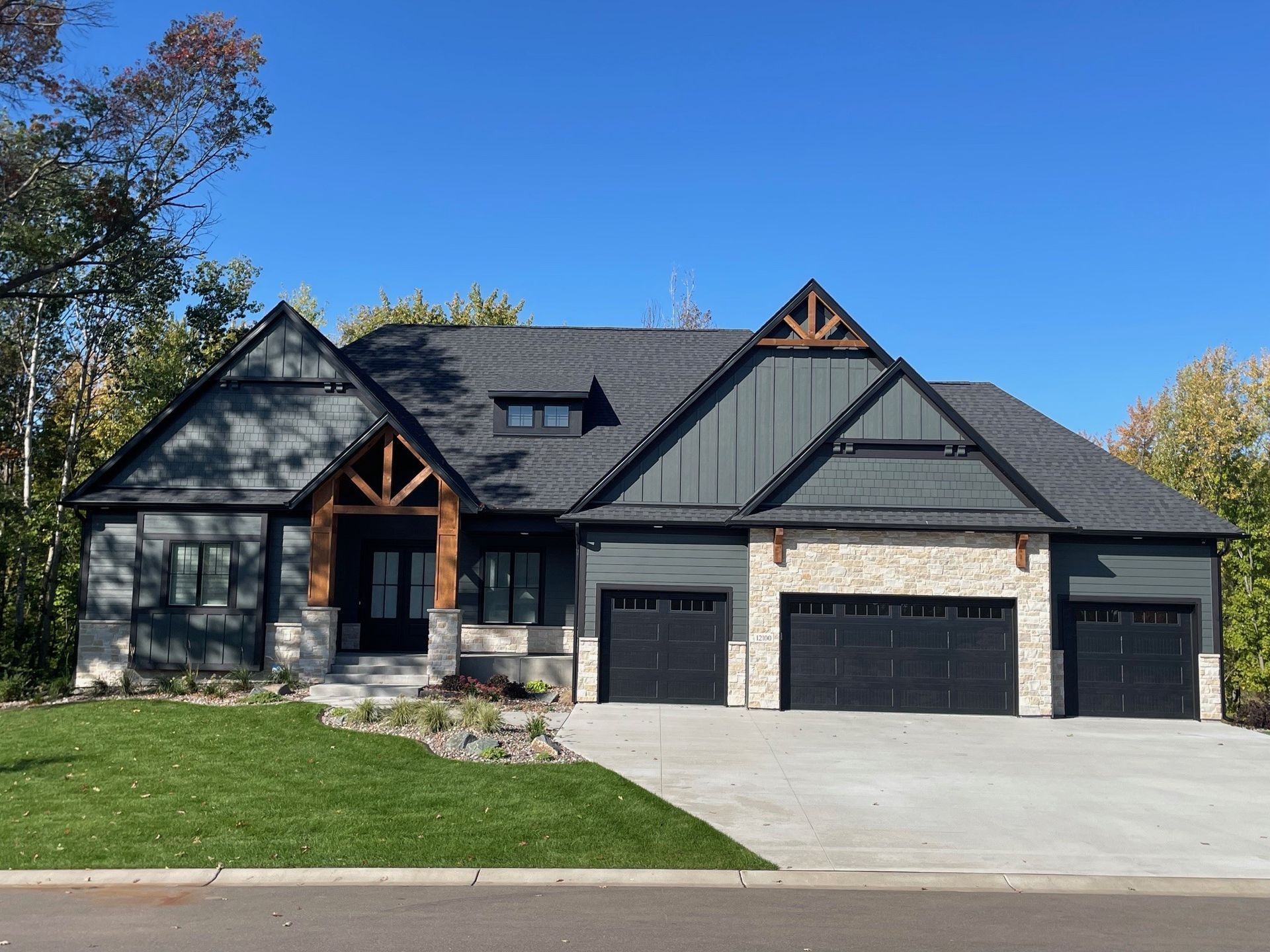 A large house with three garage doors is sitting on top of a lush green lawn.