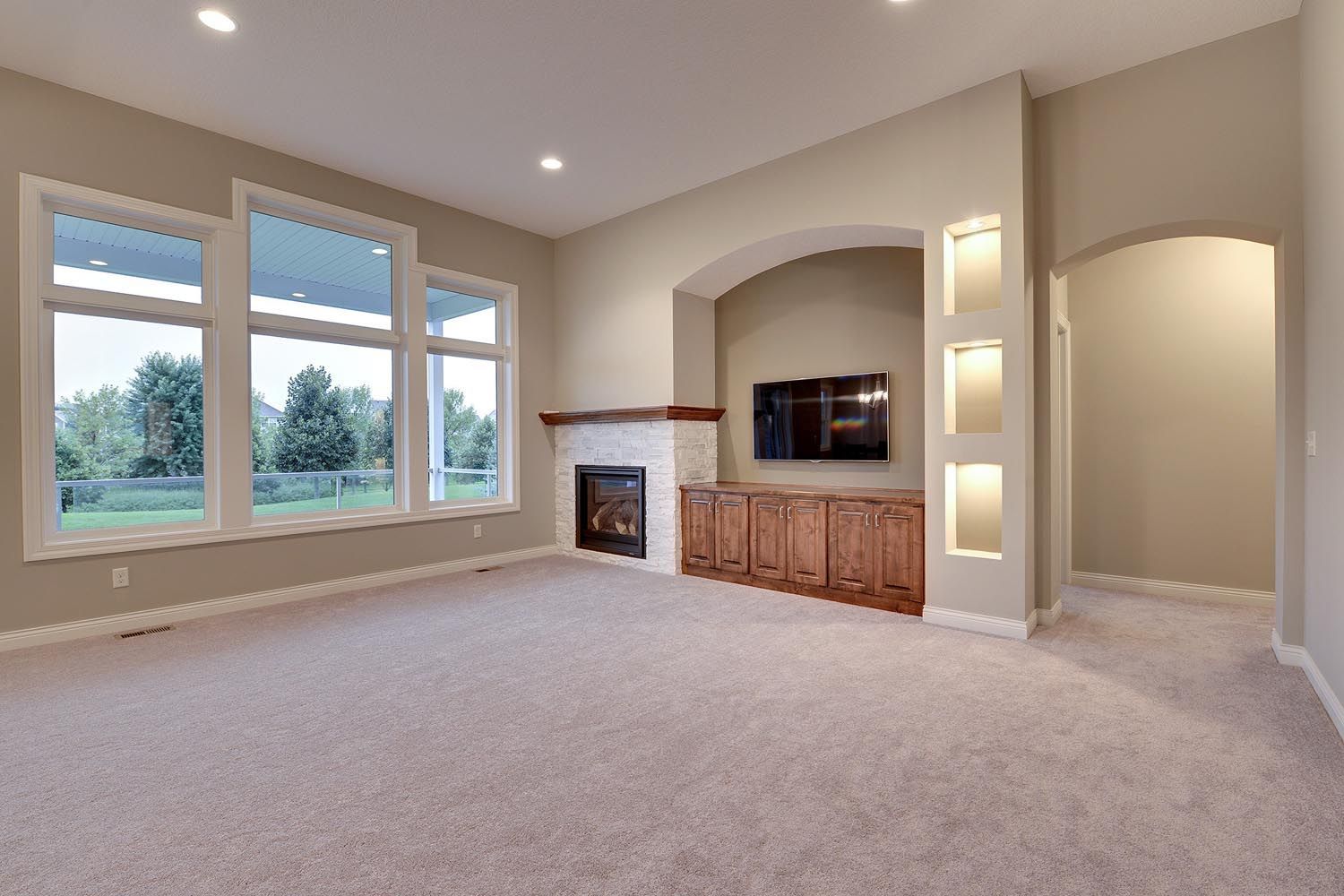 an empty living room with a fireplace and a flat screen tv