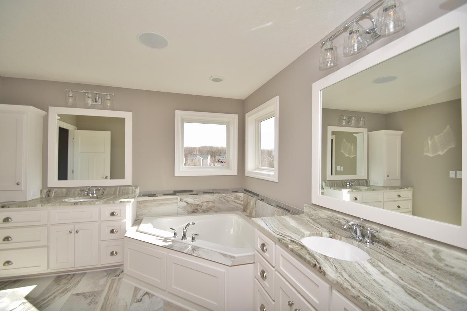 a bathroom with two sinks, a tub, and two mirrors