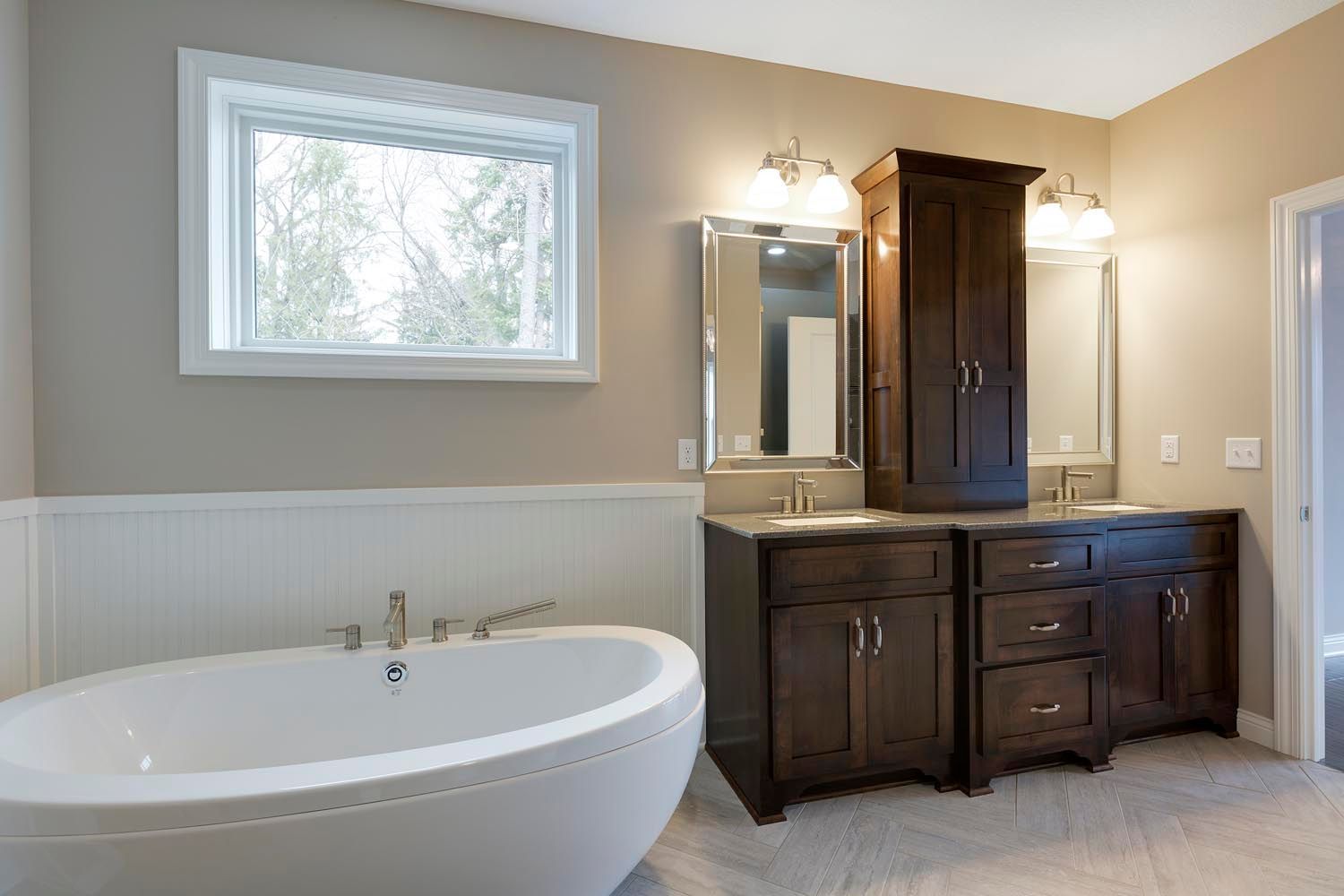 a bathroom with a tub, sinks, cabinets and a window