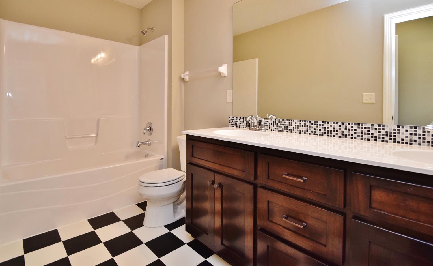 a bathroom with a toilet, sink, bathtub and checkered floor