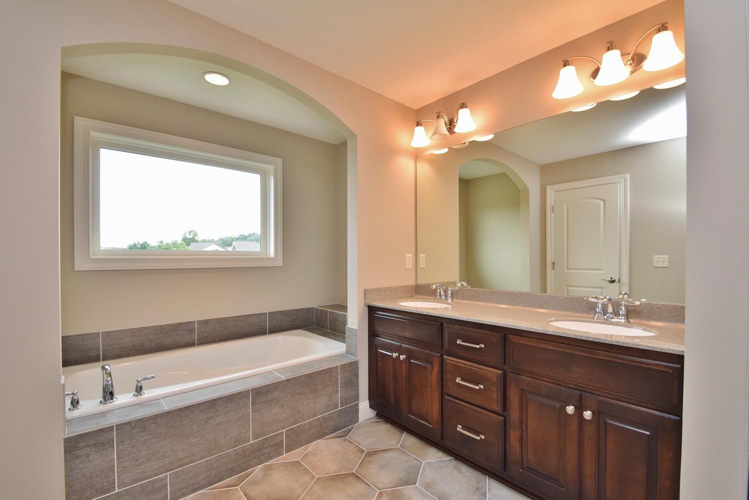 a bathroom with two sinks, a tub and a large mirror