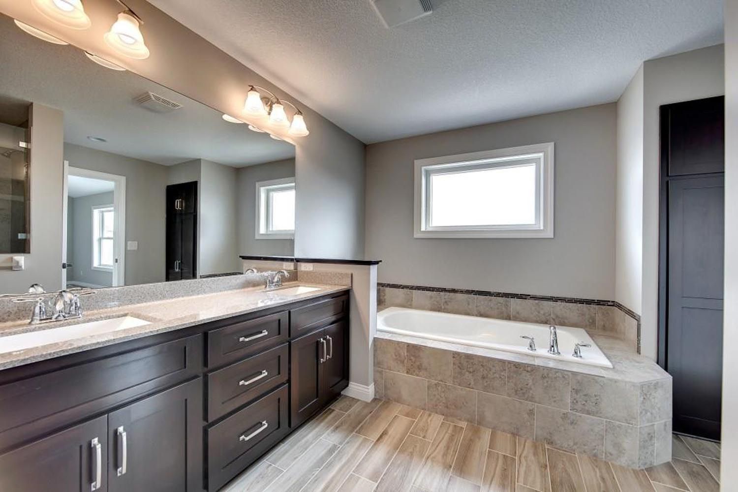 a bathroom with two sinks, a tub and a large mirror