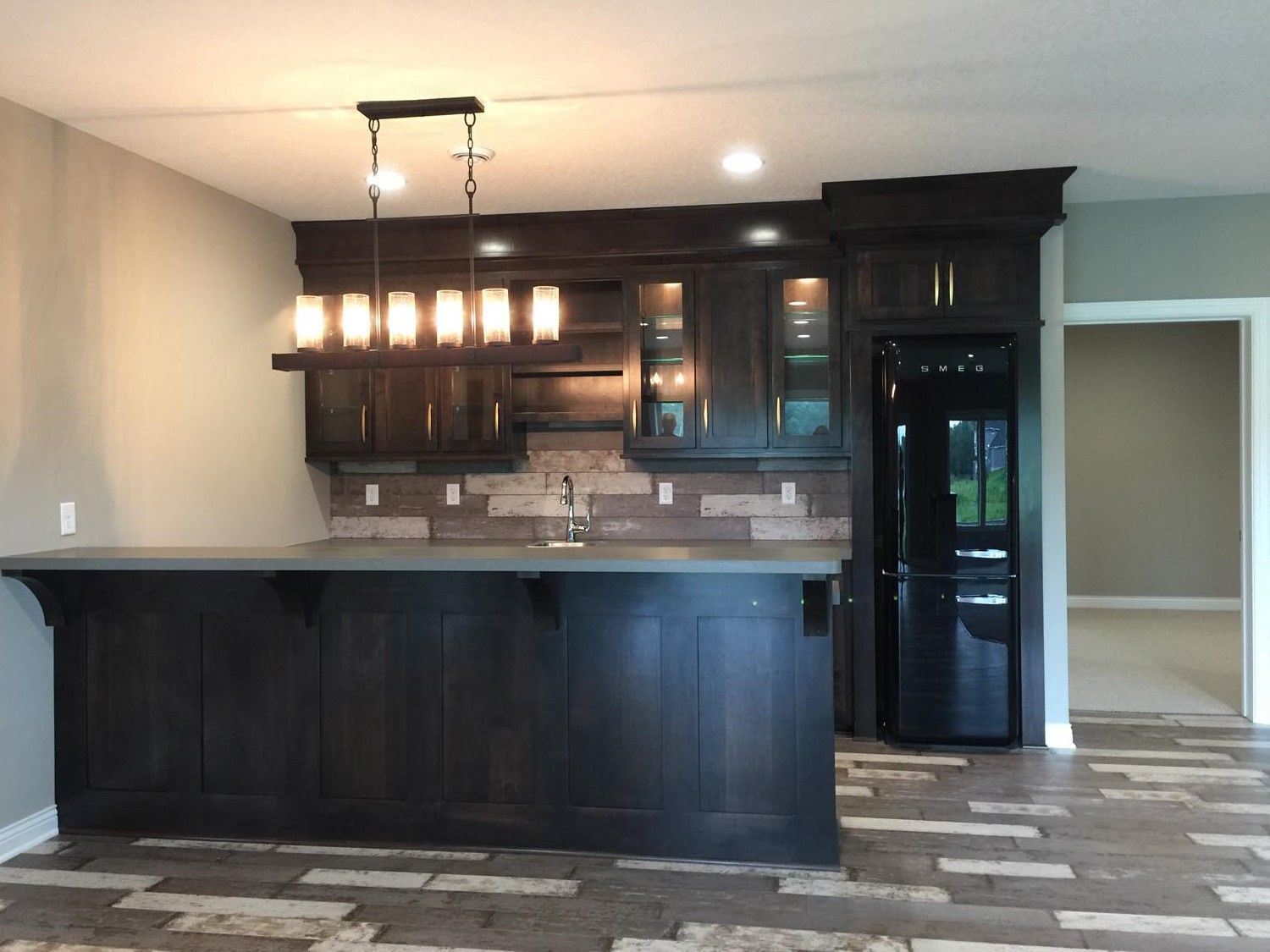 an empty kitchen with a bar and a refrigerator