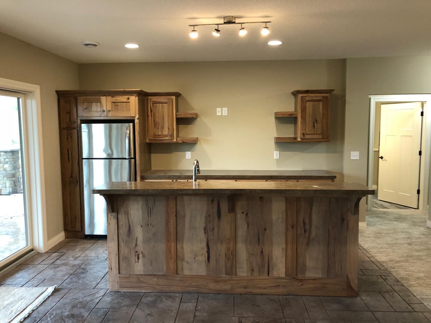 a kitchen with a large wooden island and a stainless steel refrigerator