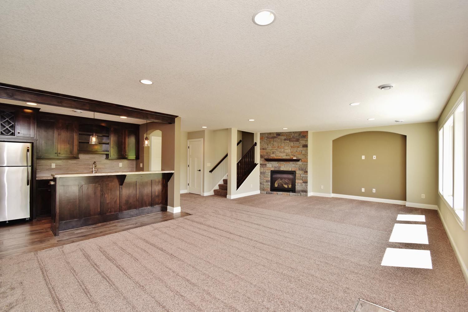 an empty basement with a fireplace and a refrigerator