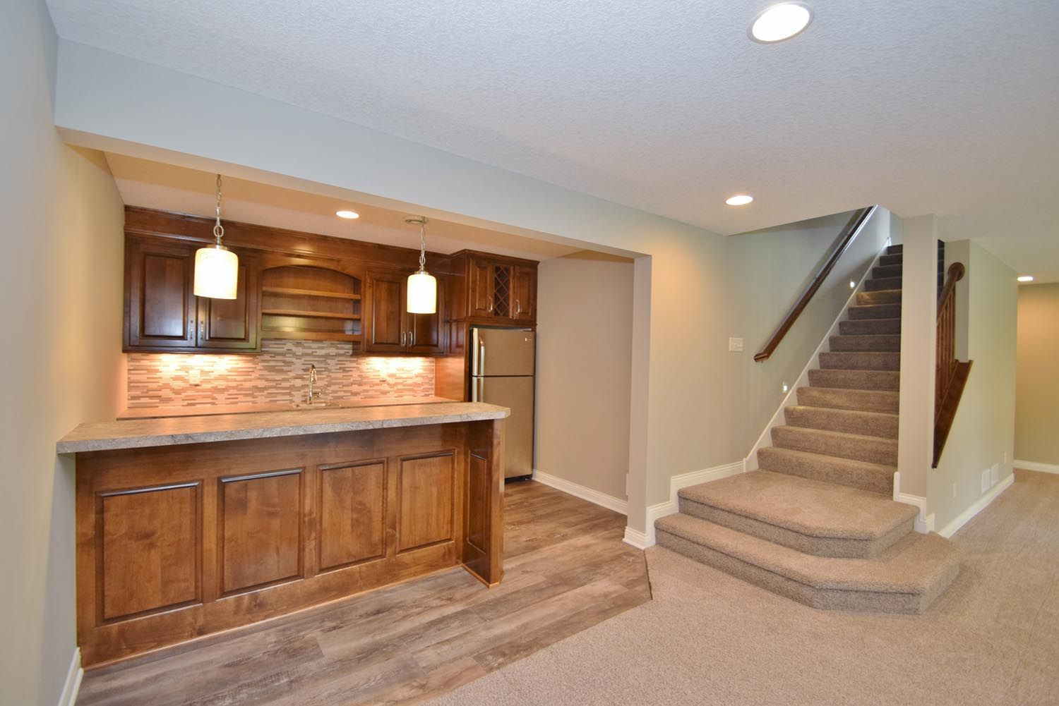 a basement with a bar and stairs leading up to the second floor