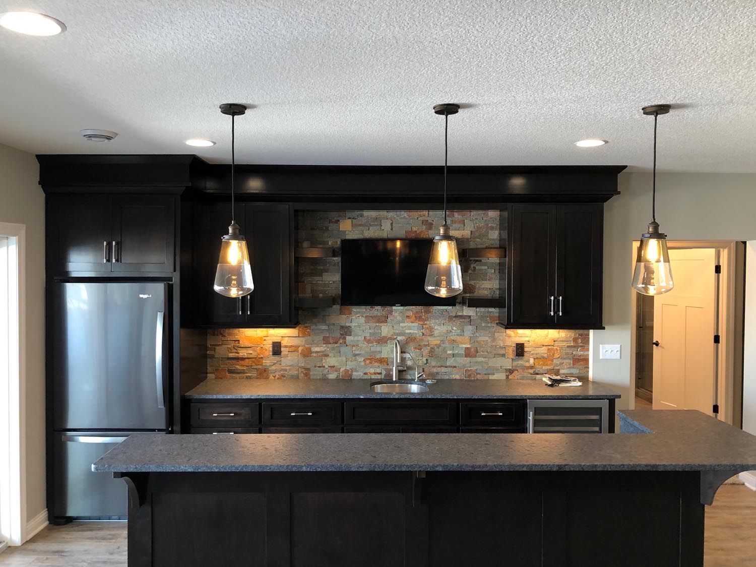 a kitchen with black cabinets and a stainless steel refrigerator