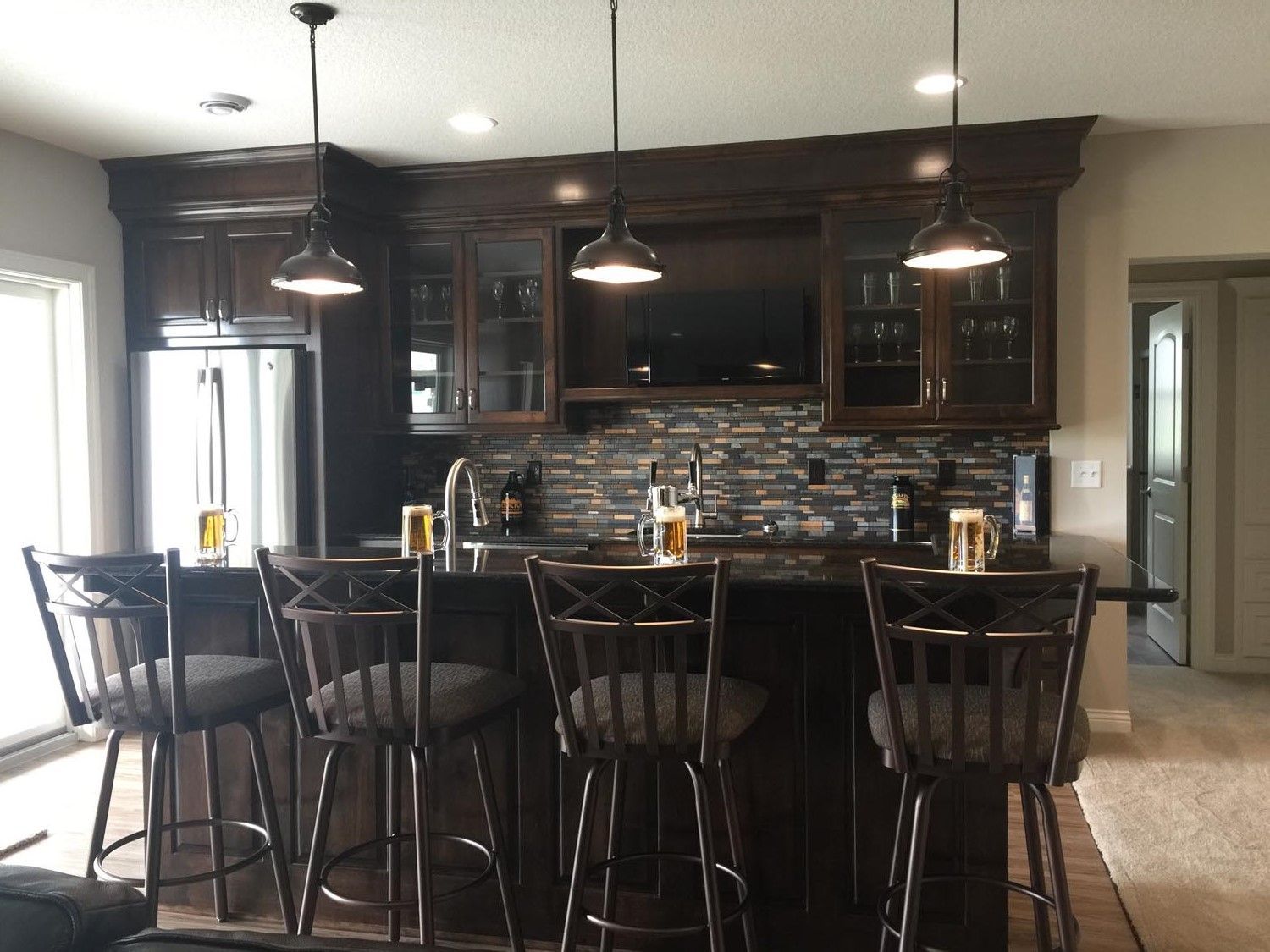 a kitchen with a bar and stools and a refrigerator