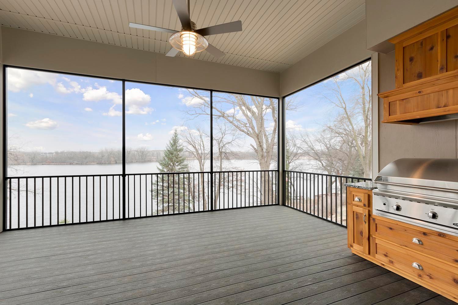 a screened in porch with a grill and a view of a lake