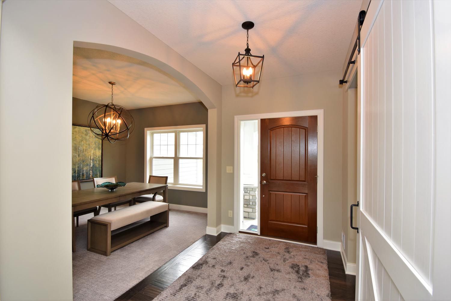 a hallway leading to a dining room with a table and bench