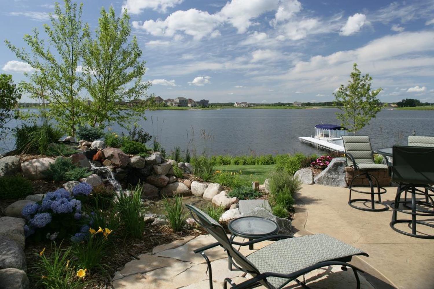 a patio with chairs and a table overlooking a lake