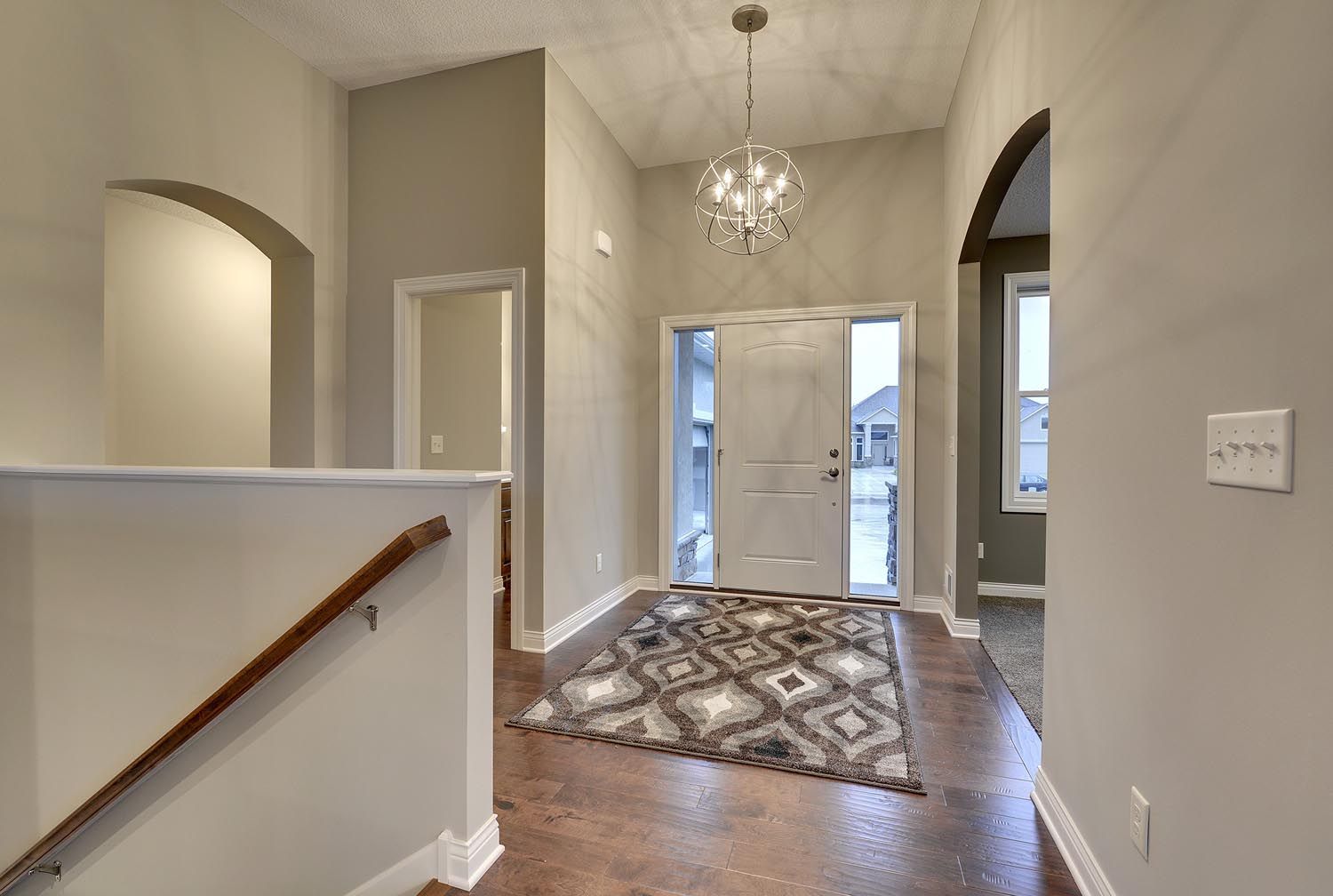 a hallway in a house with a rug and a chandelier hanging from the ceiling