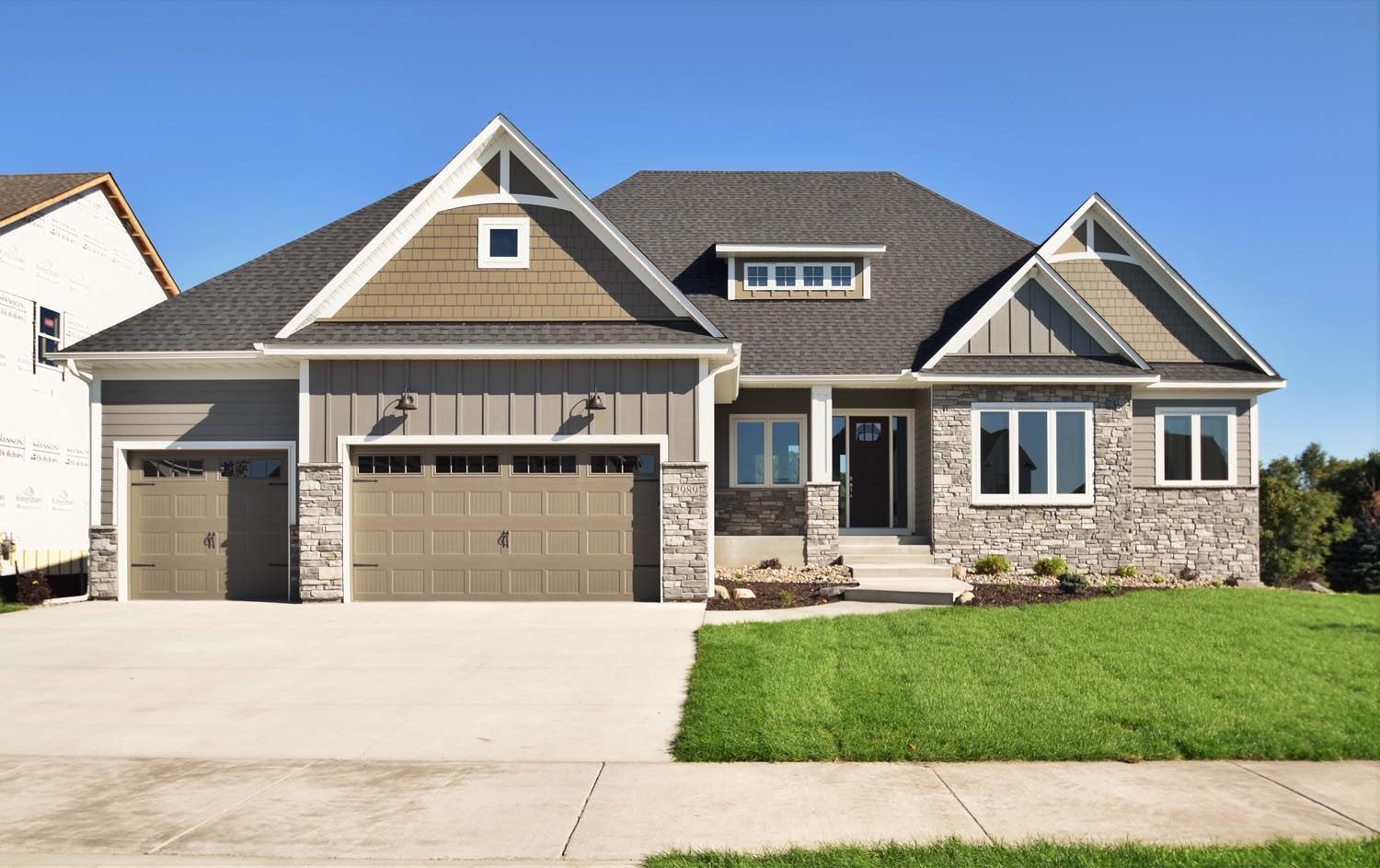 a large house with a gray roof and brown garage doors