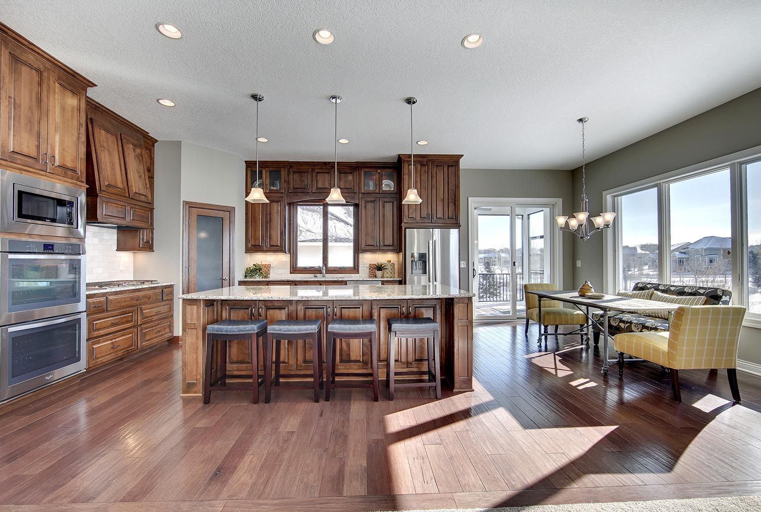 a kitchen with wooden cabinets, stainless steel appliances, a large island and a dining room