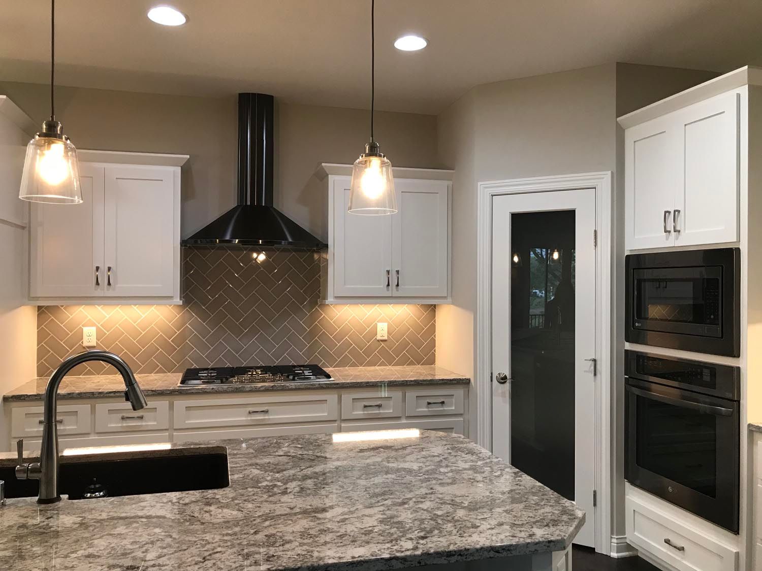 a kitchen with white cabinets, granite counter tops, a stove, sink, and ovens