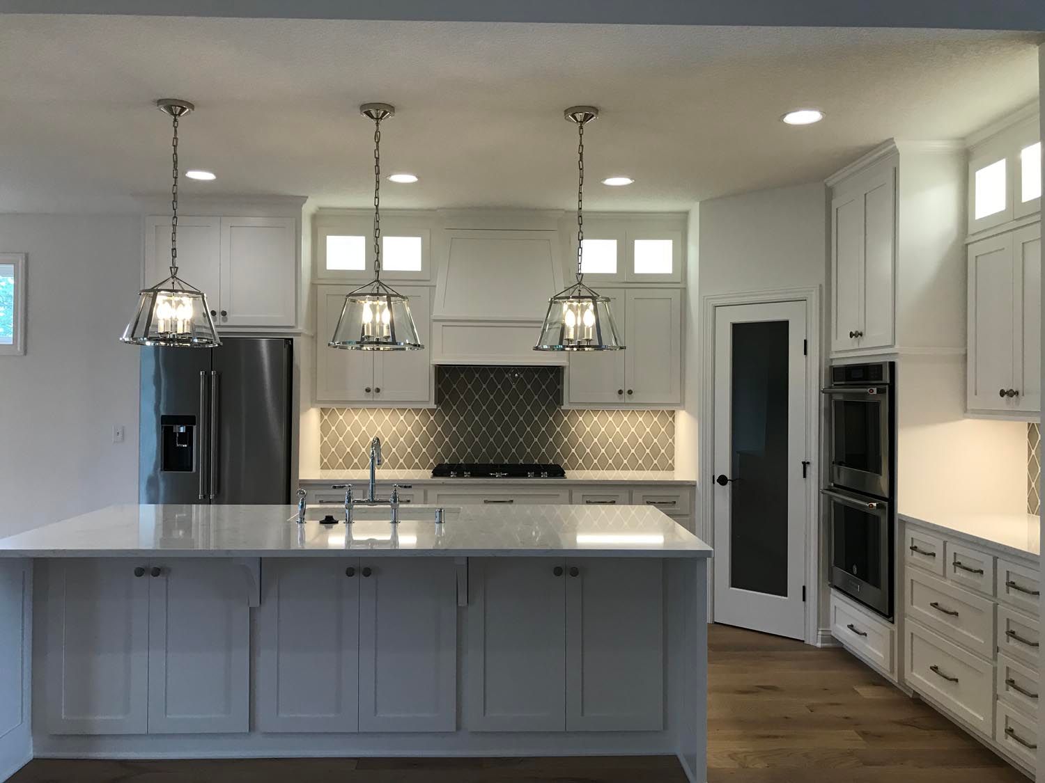 a kitchen with white cabinets, stainless steel appliances, and a large island