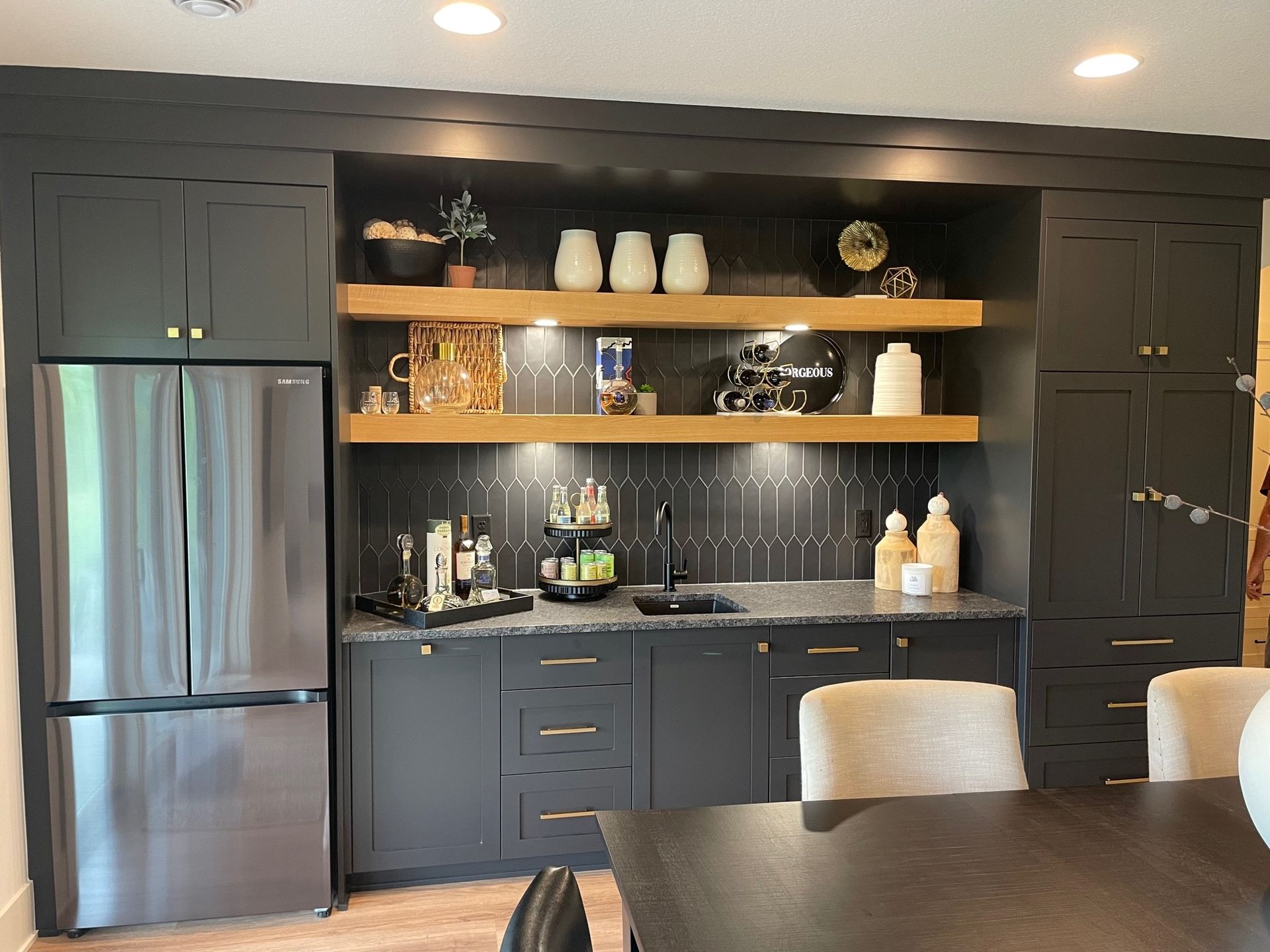 a kitchen with black cabinets, stainless steel appliances, a table and chairs