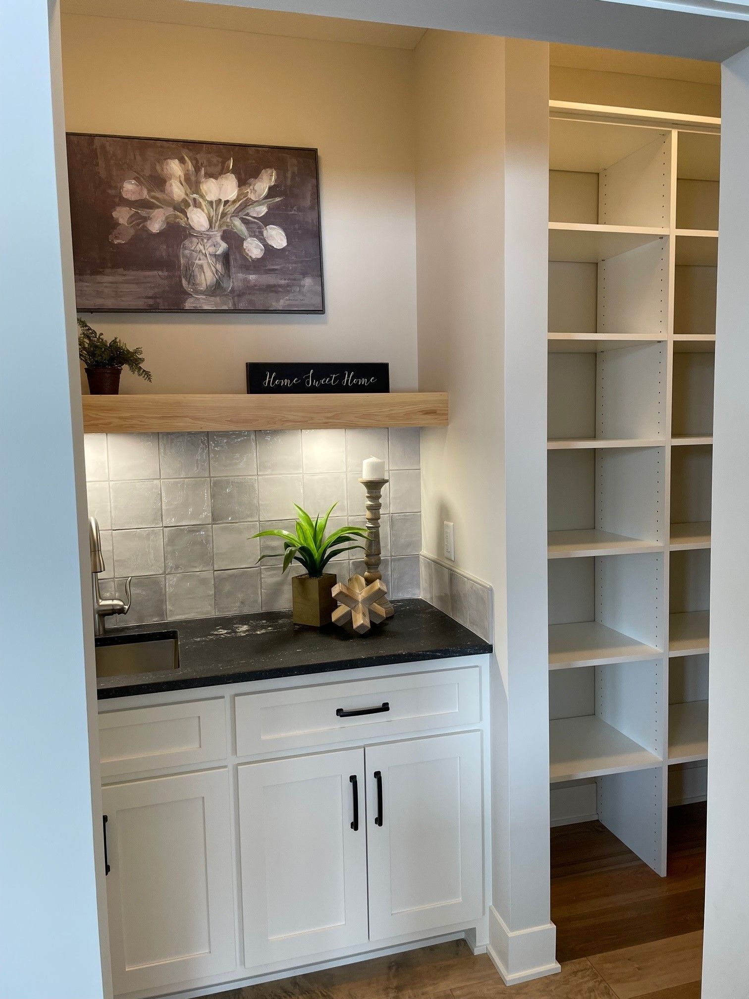a kitchen with a sink , cabinets , shelves and a painting on the wall .