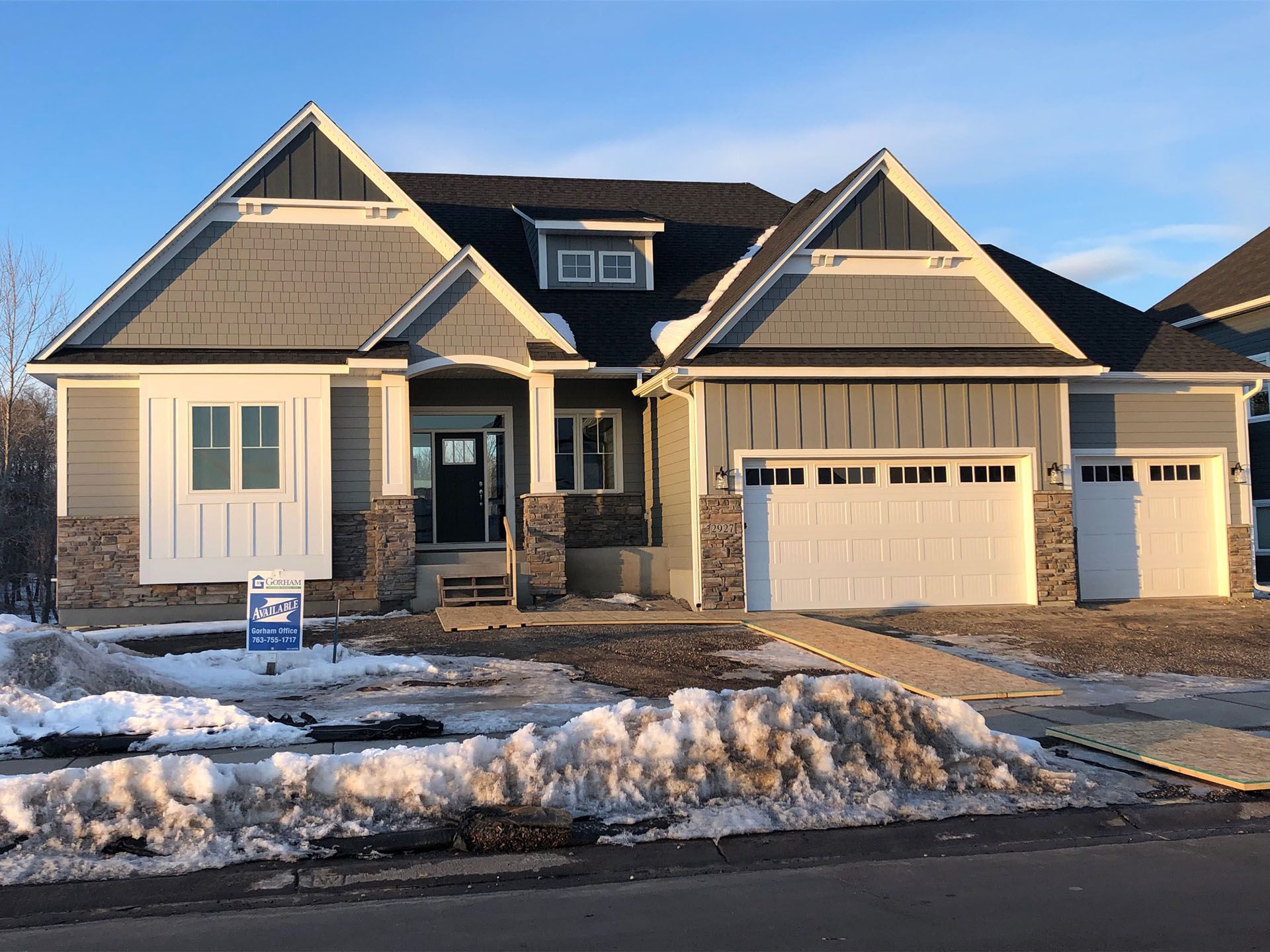 a large house with a lot of snow on the ground and a for sale sign in front of it