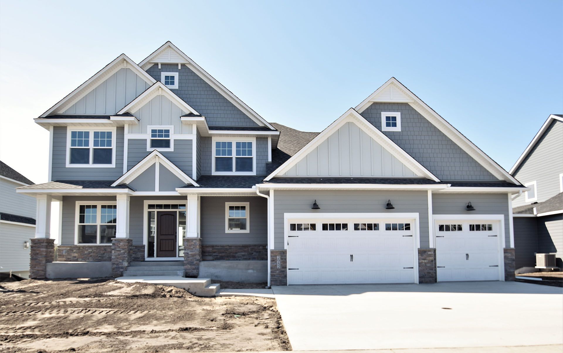 a large gray and white house with a lot of windows and garage doors