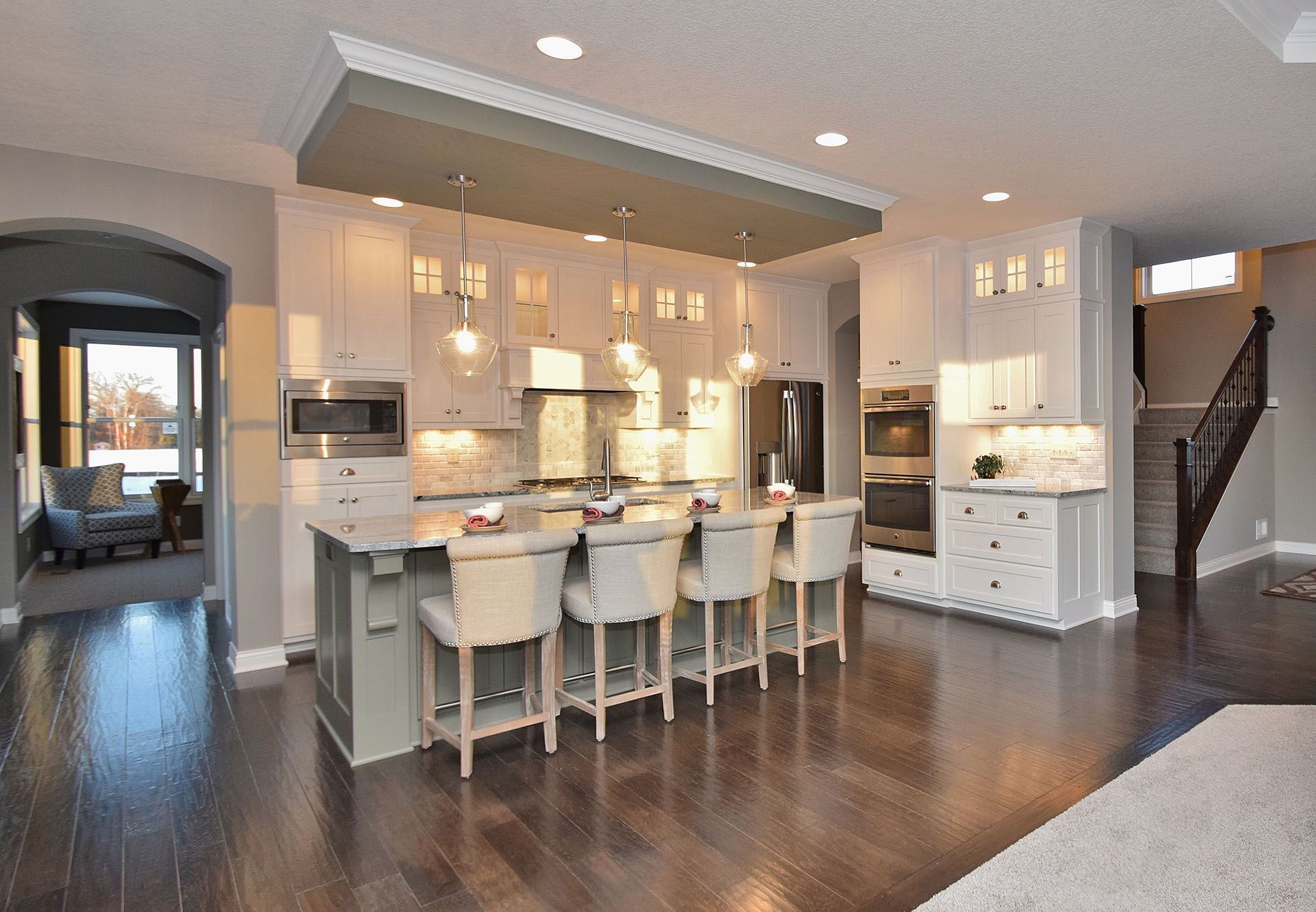 a kitchen with white cabinets and stools and a large island .