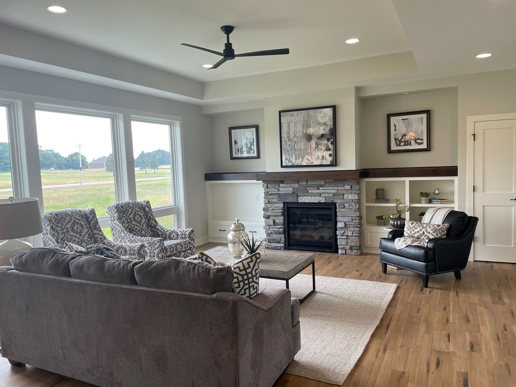 a living room with a couch , chairs , a fireplace and a ceiling fan .