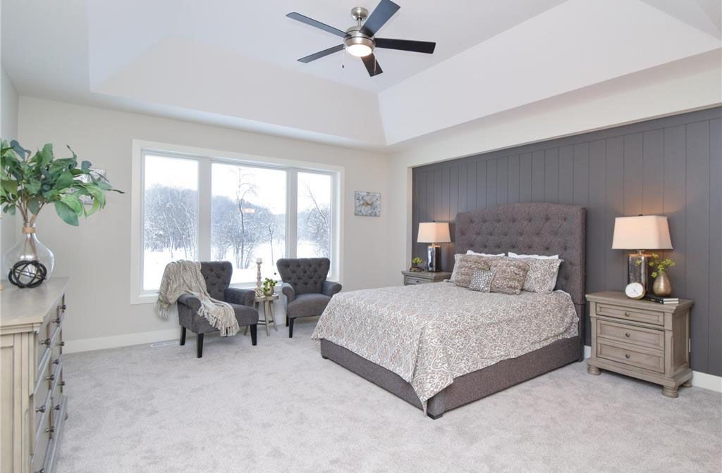 a bedroom with a bed, chairs, nightstands and a ceiling fan