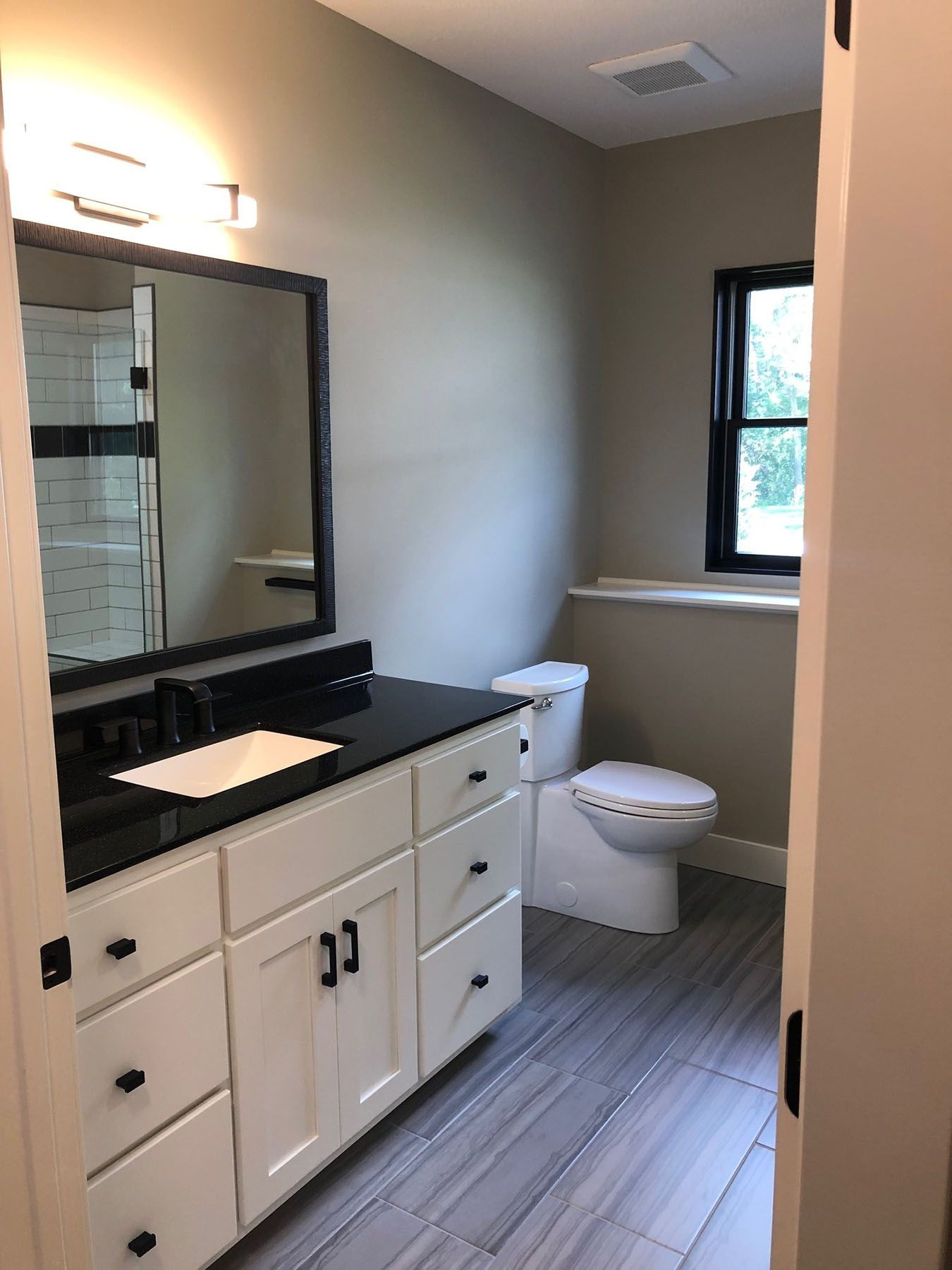 a bathroom with a toilet, sink, mirror and window