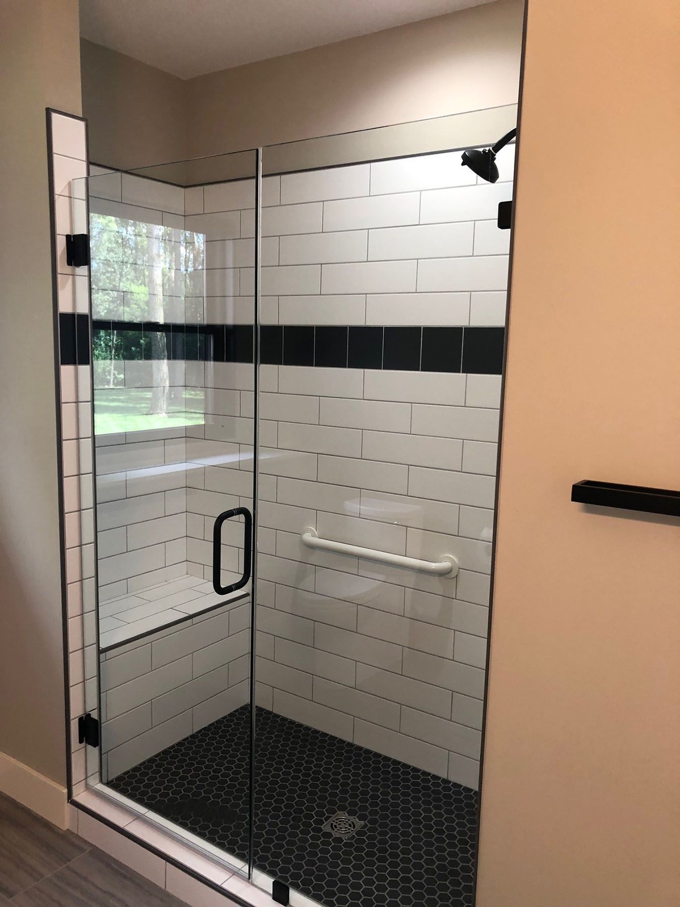 a bathroom with a walk-in shower with black and white tiles and a glass door