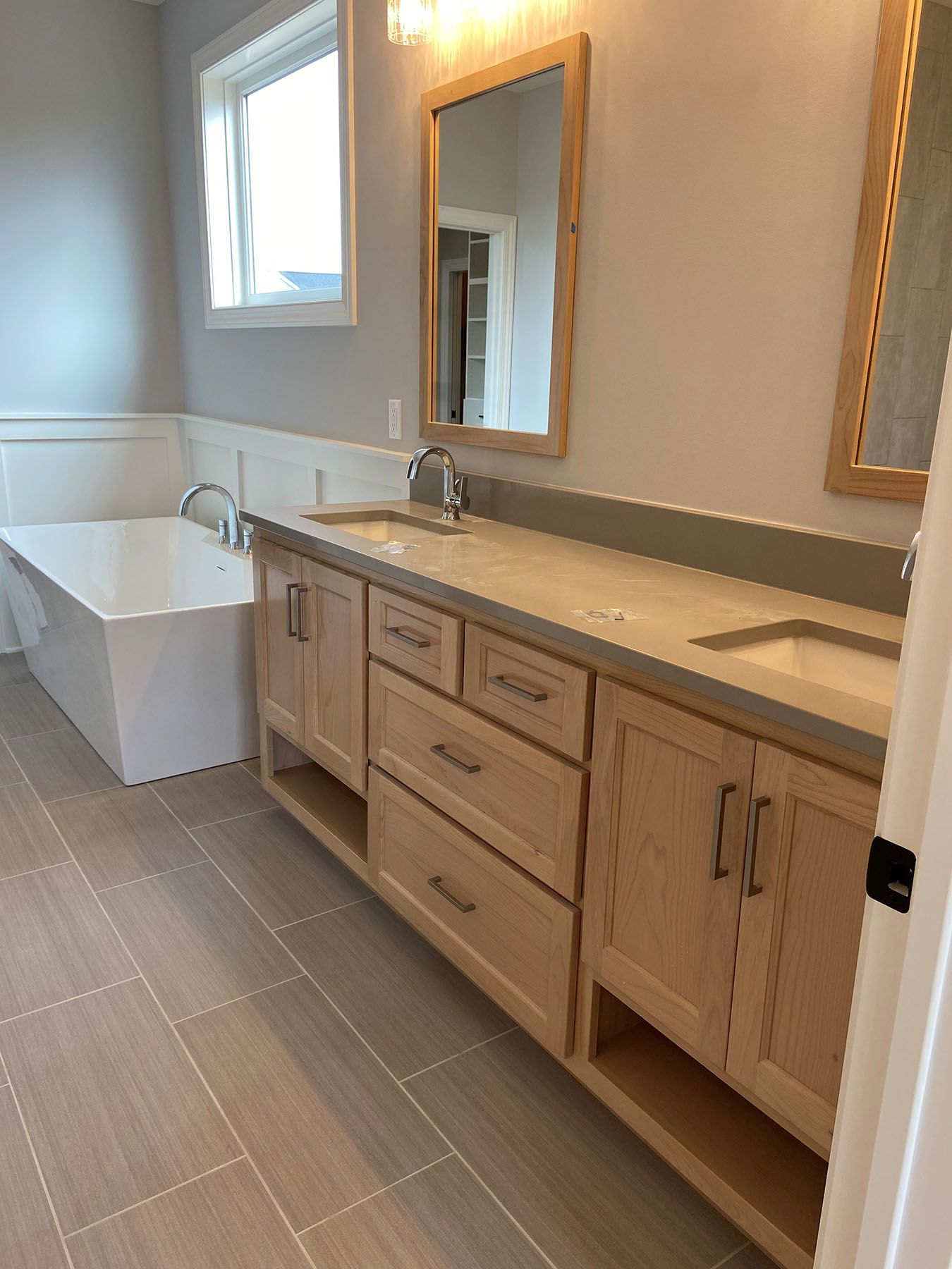 a bathroom with two sinks, a tub, and a mirror.