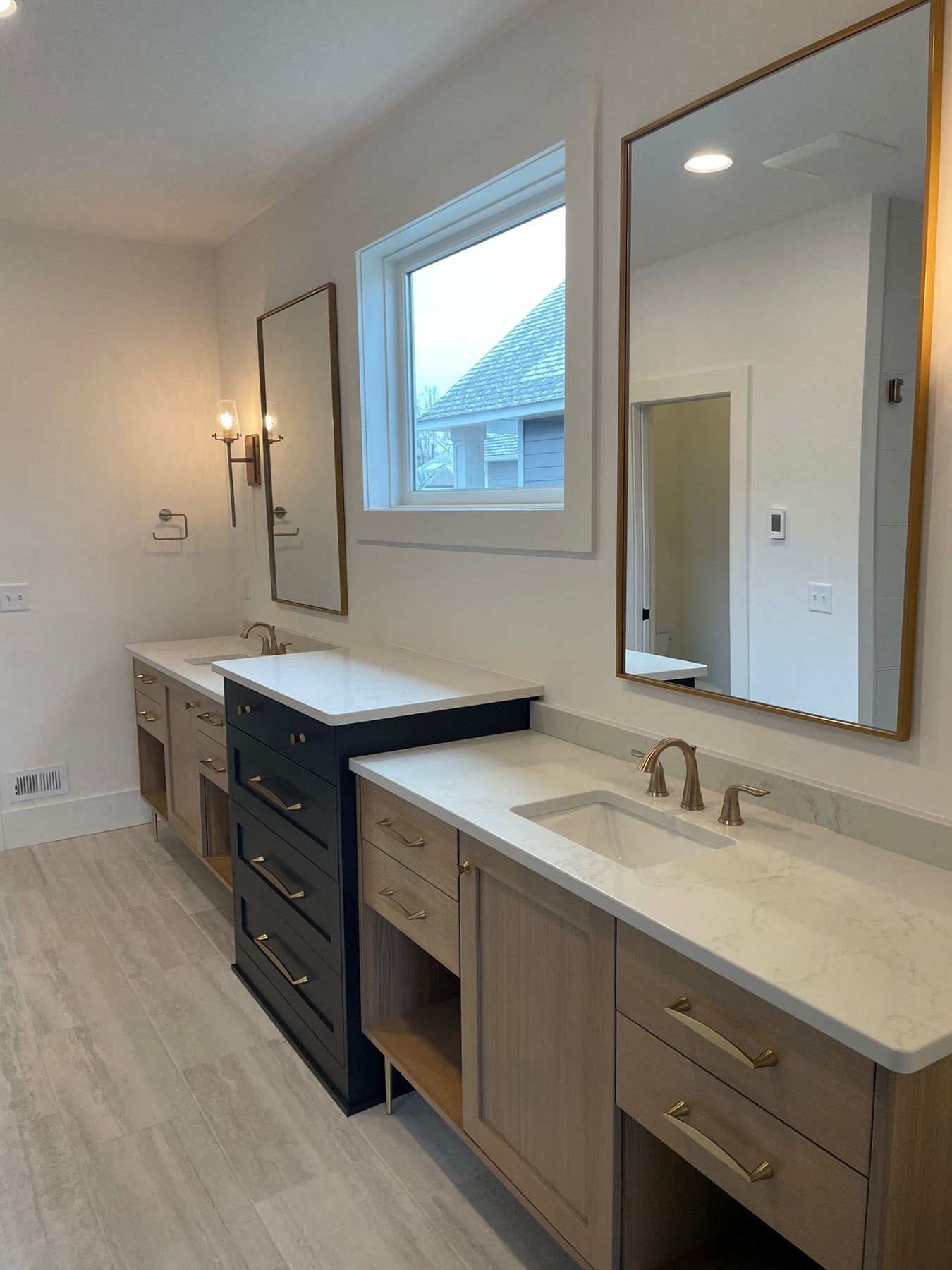 a bathroom with two sinks, two mirrors and a window