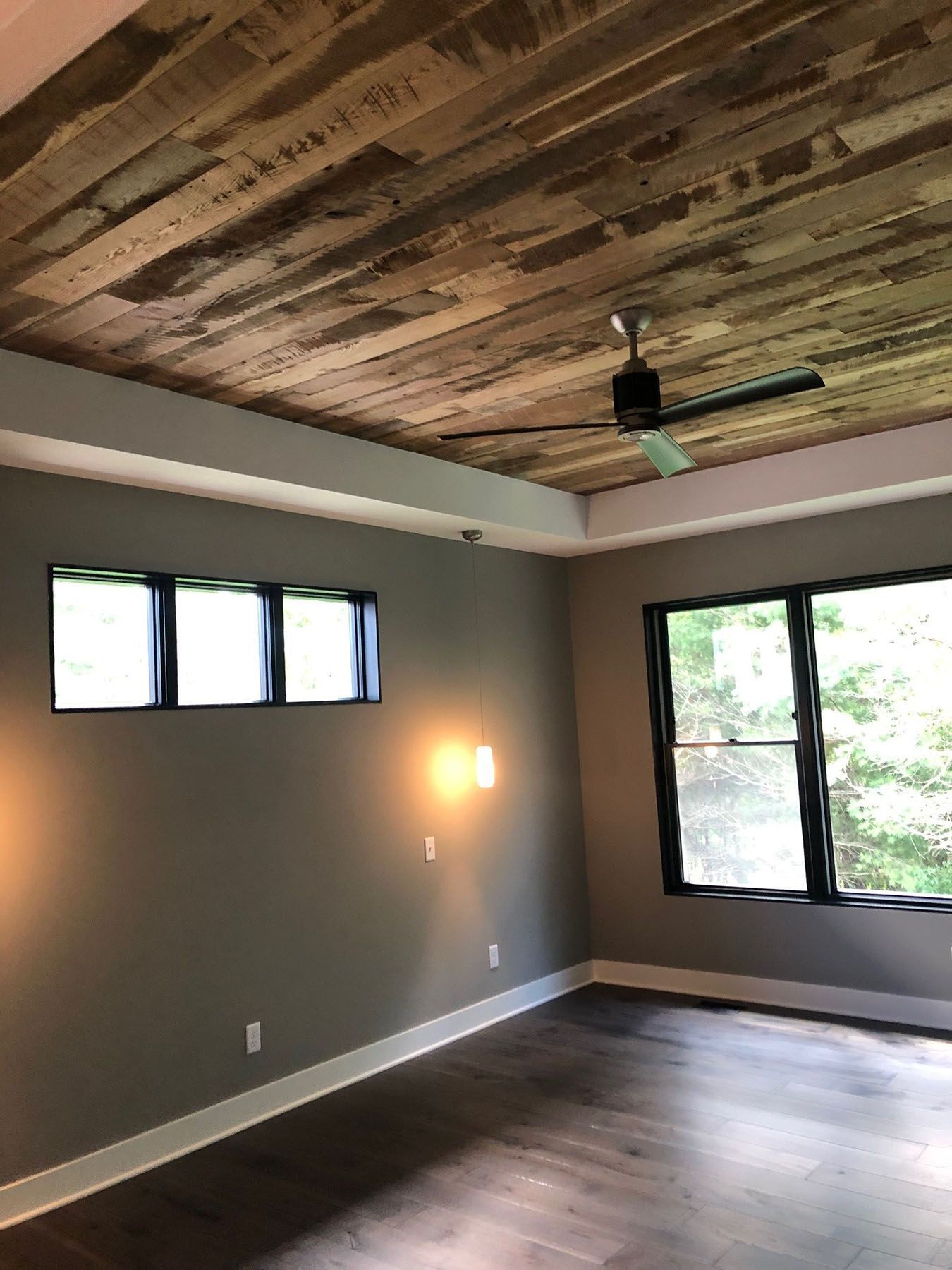 an empty room with a wooden ceiling and a ceiling fan