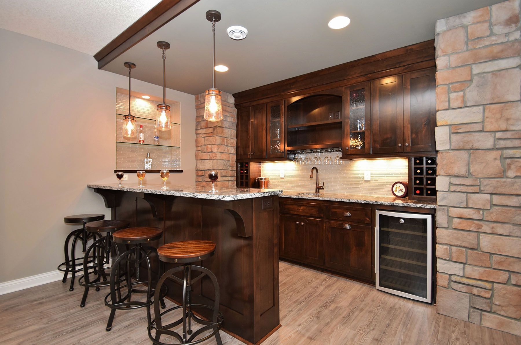 a kitchen with a bar and stools and a wine cooler 