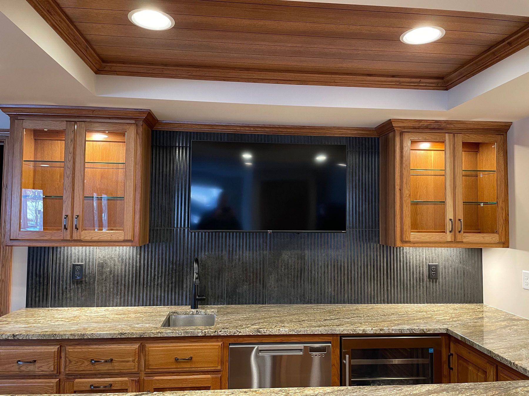 a kitchen with wooden cabinets, granite countertop, stainless steel appliances and a flat screen tv