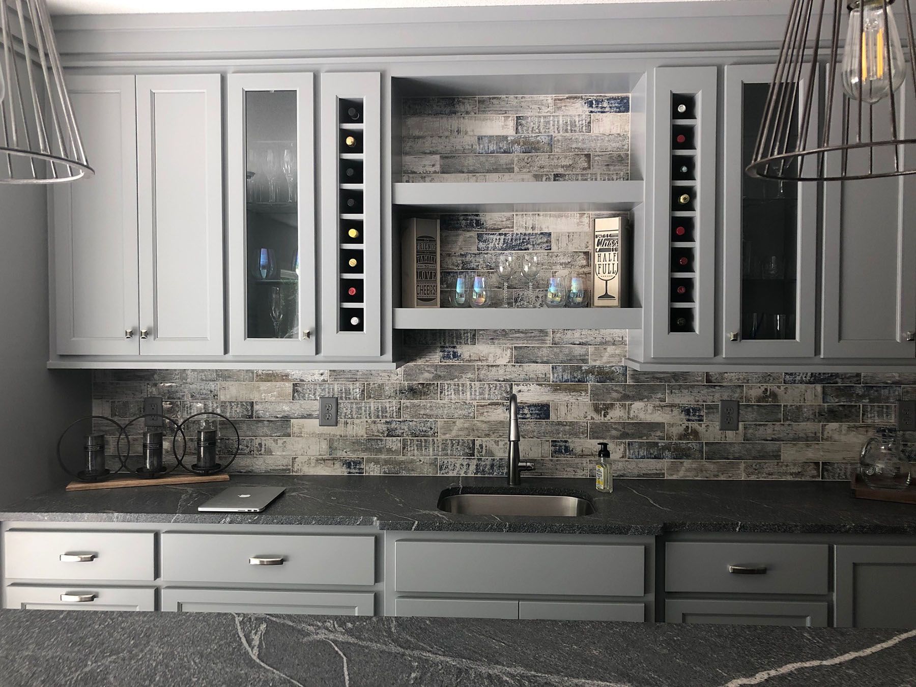 a kitchen with a sink, cabinets, and a brick wall