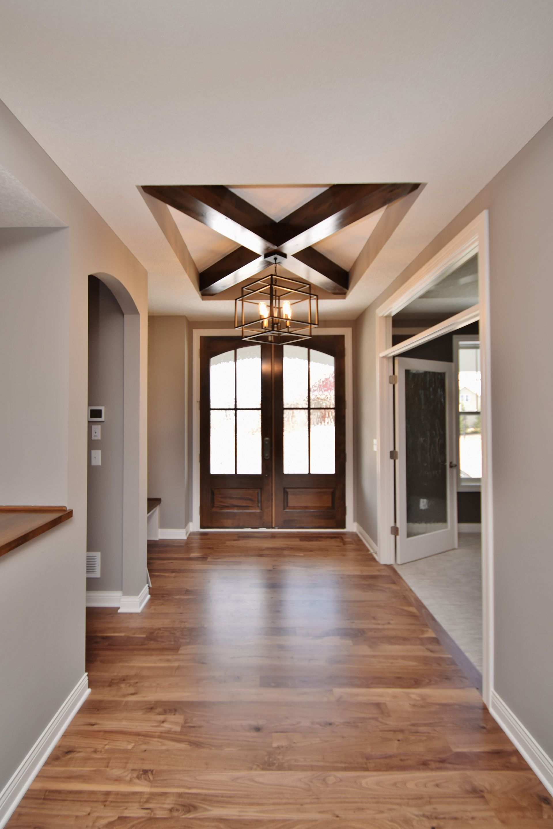 a hallway with hardwood floors and a chandelier hanging from the ceiling 