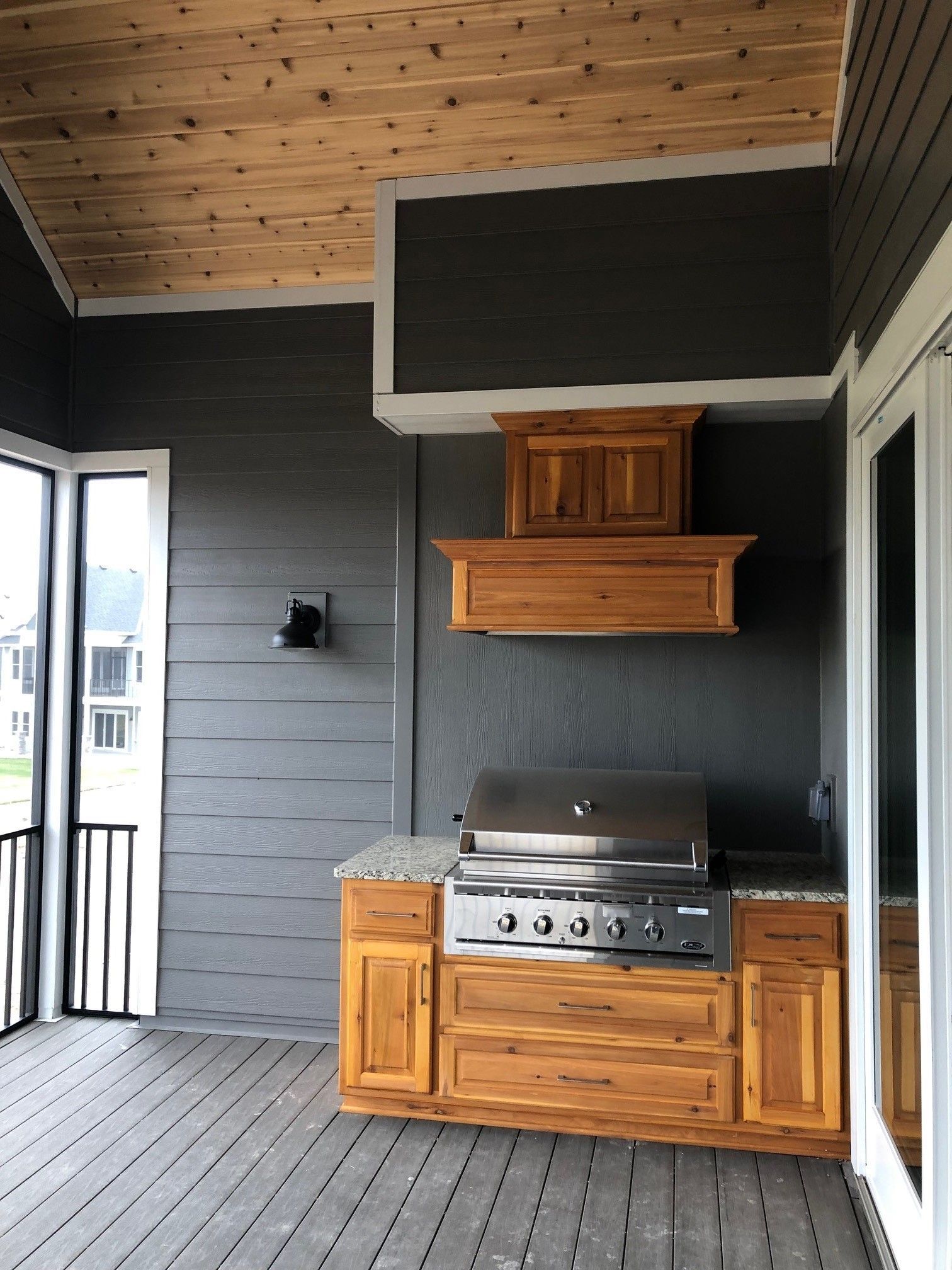 a screened in porch with a grill and cabinets