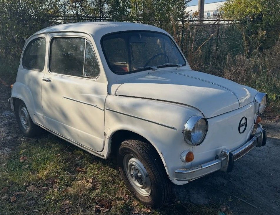 White vintage Fiat 600 parked on grass next to a road