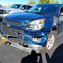 Damaged blue SUV with a dented front bumper; parked outside.