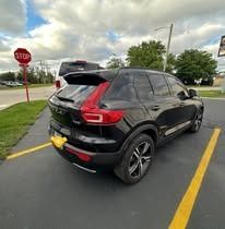 Black Volvo SUV parked near a stop sign on an asphalt lot.