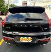 Rear view of a black Volvo SUV with a license plate featuring smiling emojis.