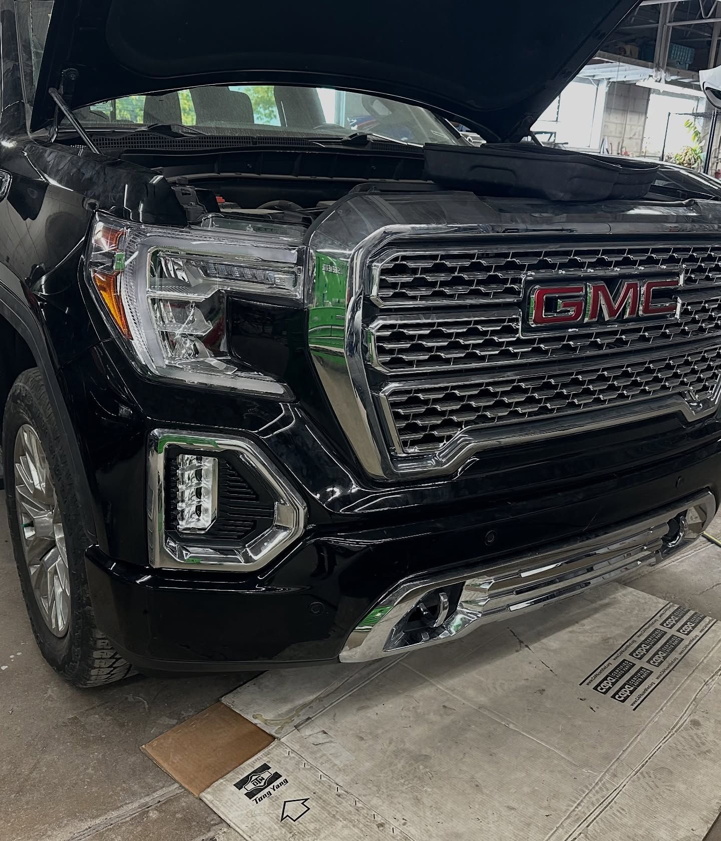 Black GMC truck with the hood open, parked in a garage.