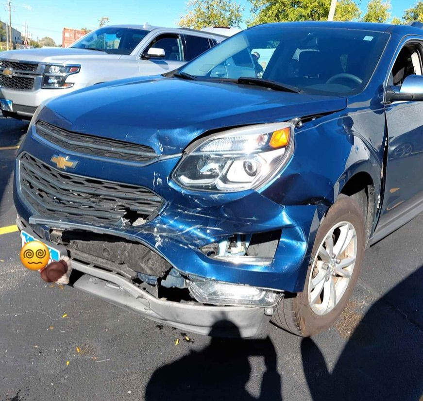 Damaged blue SUV with front-end collision damage parked next to a silver SUV in an outdoor setting.